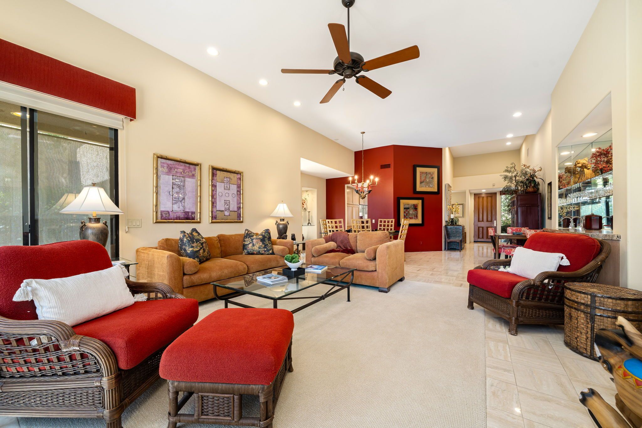 A spacious living room with a ceiling fan, two sofas, a coffee table, and a dining area with chairs.