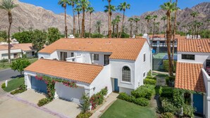 A residential area with white houses, red-tiled roofs, and palm trees. - Tennis Villa #3 - Courtside View, 2 bed, 2 bath, Permit 067145 (La Quinta)