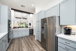 A modern kitchen with light blue cabinets, stainless steel appliances, and a coffee maker on the counter.