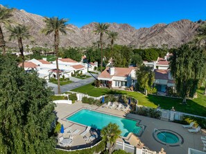 A residential area with a swimming pool, houses, and palm trees.