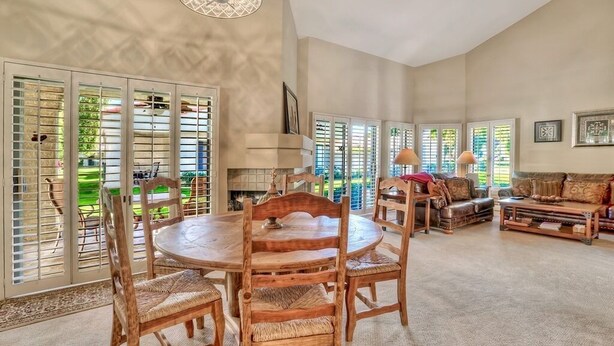 A spacious living room with a round wooden table and chairs, a sofa, and a fireplace. - Santa Rosa Cove #16 - Greenbelt, 3 bedroom/3.5 bath, permit 063424 (La Quinta)