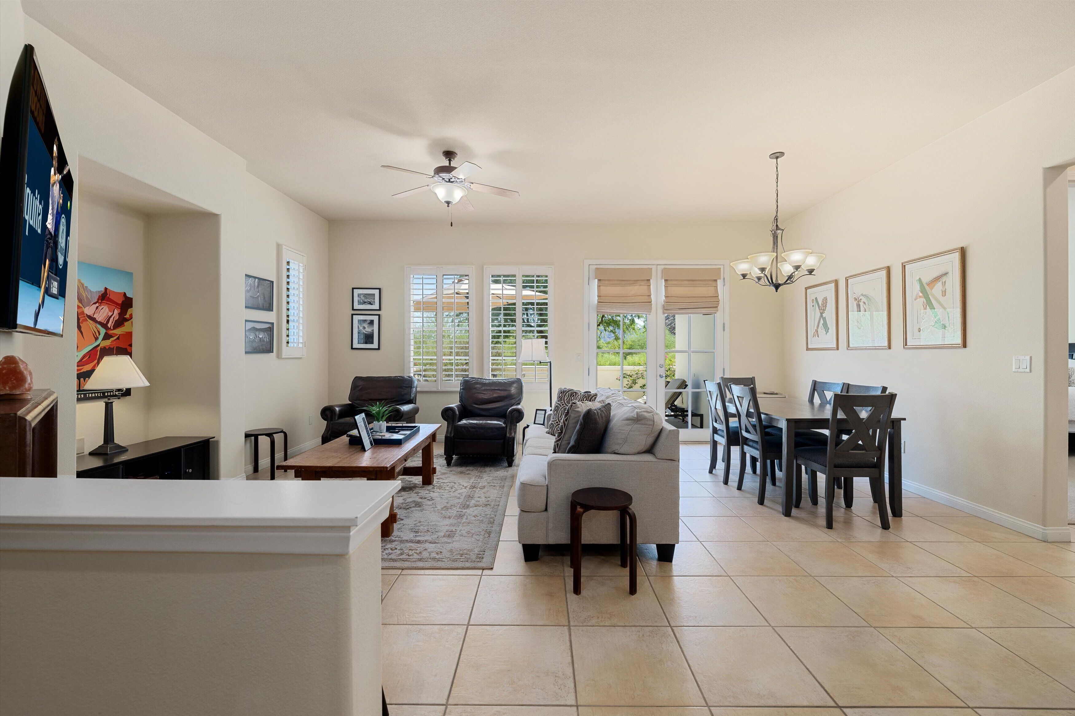 A spacious living room with a sofa, chairs, a dining table, and a ceiling fan.