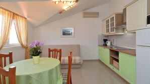 A small, cozy kitchen with a dining area, featuring a table with chairs, a bench, and a vase of flowers. - Apartment 31/41 (Istria - Valbandon), 600m from the beach (Valbandon)