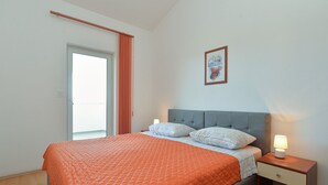 A bedroom with a bed, a nightstand, a lamp, a window with curtains, and a framed picture on the wall. - Apartment 31/41 (Istria - Valbandon), 600m from the beach (Valbandon)
