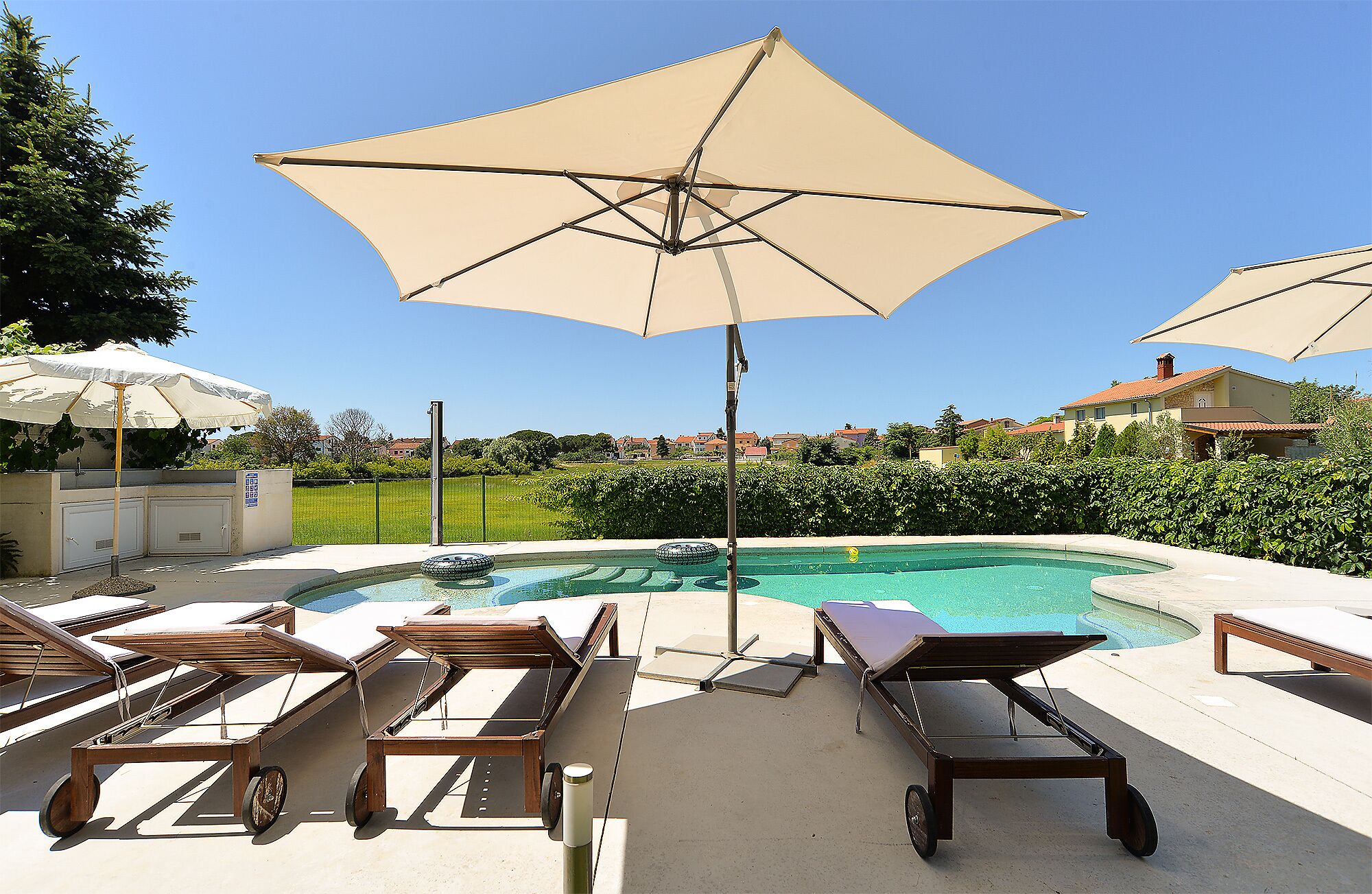Een zwembadterras met ligbedden, een zwembad en parasols.