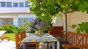 A patio with a table and chairs, surrounded by plants and a building in the background. - Apartment 31/41 (Istria - Valbandon), 600m from the beach (Valbandon)