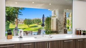 A kitchen with a large window overlooking a golf course and mountains. - PGA West #11 - 3 bedroom Pool Home -Weiskopf, LQ permit #111254 (La Quinta)