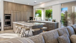 A modern kitchen with a large island, bar stools, and built-in appliances. - PGA West #11 - 3 bedroom Pool Home -Weiskopf, LQ permit #111254 (La Quinta)