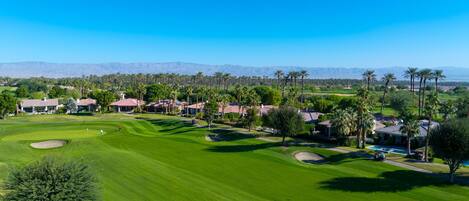 A golf course with a clear view of the fairway, sand bunkers, and a clubhouse.