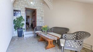 An outdoor seating area with a stone floor, a wooden table, and two chairs. - Apartment 38/49 (Istria - Valbandon), 750m from the beach (Valbandon)