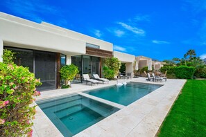 A modern house with a swimming pool, outdoor furniture, and a well-maintained lawn.