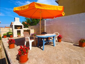 An outdoor patio with a stone barbecue, a blue table, white chairs, and potted plants. - Apartment 39/50 (Istria - Banjole), 500m from the beach (Banjole)