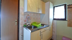 A compact kitchen with white cabinets, a stainless steel sink, and a window with a curtain. - Apartment 41/23324 (Istria - Stinjan), 700m from the beach (Stinjan)