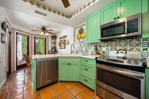 Una cucina con mobili verdi, una lavastoviglie in acciaio inossidabile, un piano cottura e un forno a microonde.