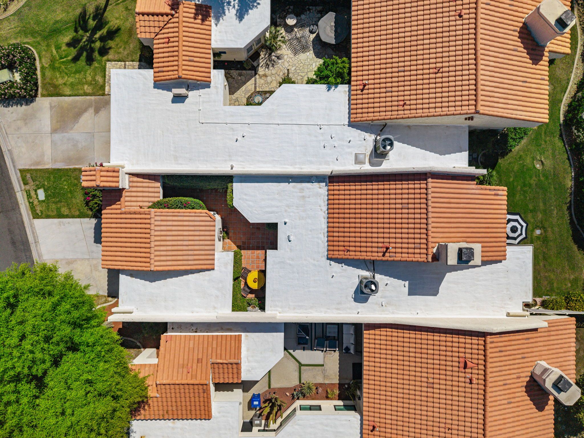 A multi-story building with multiple roof terraces, some with tiled roofs and others with flat roofs.