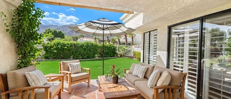 Un patio con mobiliario exterior, una mesa y una planta en maceta.