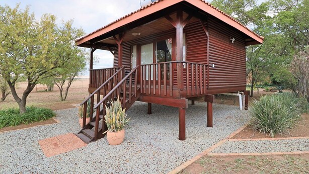 A wooden cabin with a porch and a staircase leading to the entrance. - Tata Farm Game Lodge (Hammanskraal)
