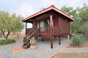 A wooden cabin with a porch and a staircase leading to the entrance. - Tata Farm Game Lodge (Hammanskraal)