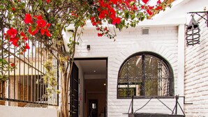 Un patio con un sendero, una parrilla y un edificio blanco con una verja negra.