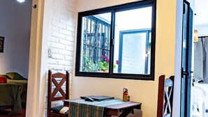 Un comedor con mesa y sillas, una ventana con vistas y un ventilador de techo.