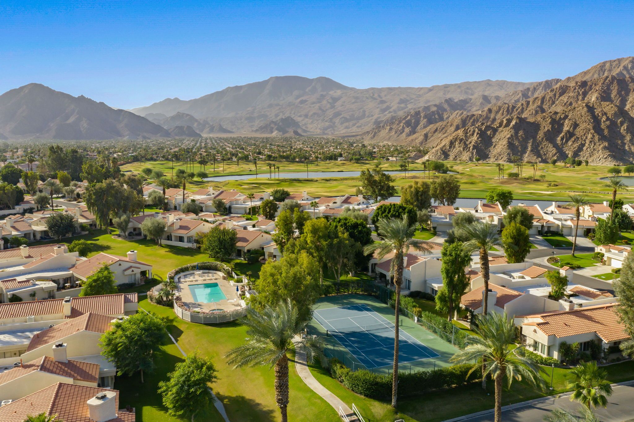 A residential area with houses, a tennis court, and a swimming pool.