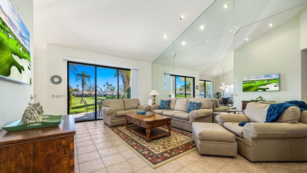 A spacious living room with a large window, a sofa set, a coffee table, and a rug.