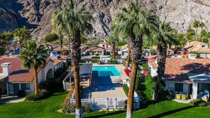 A residential area with houses, a swimming pool, and palm trees.