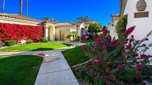 A residential area with well-maintained lawns, a pathway, and a house with a number plaque.