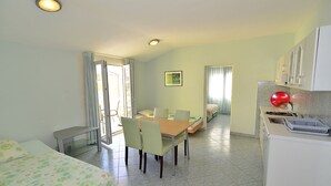 Une chambre d’hôtel compacte comprenant un coin repas, une kitchenette et un lit.