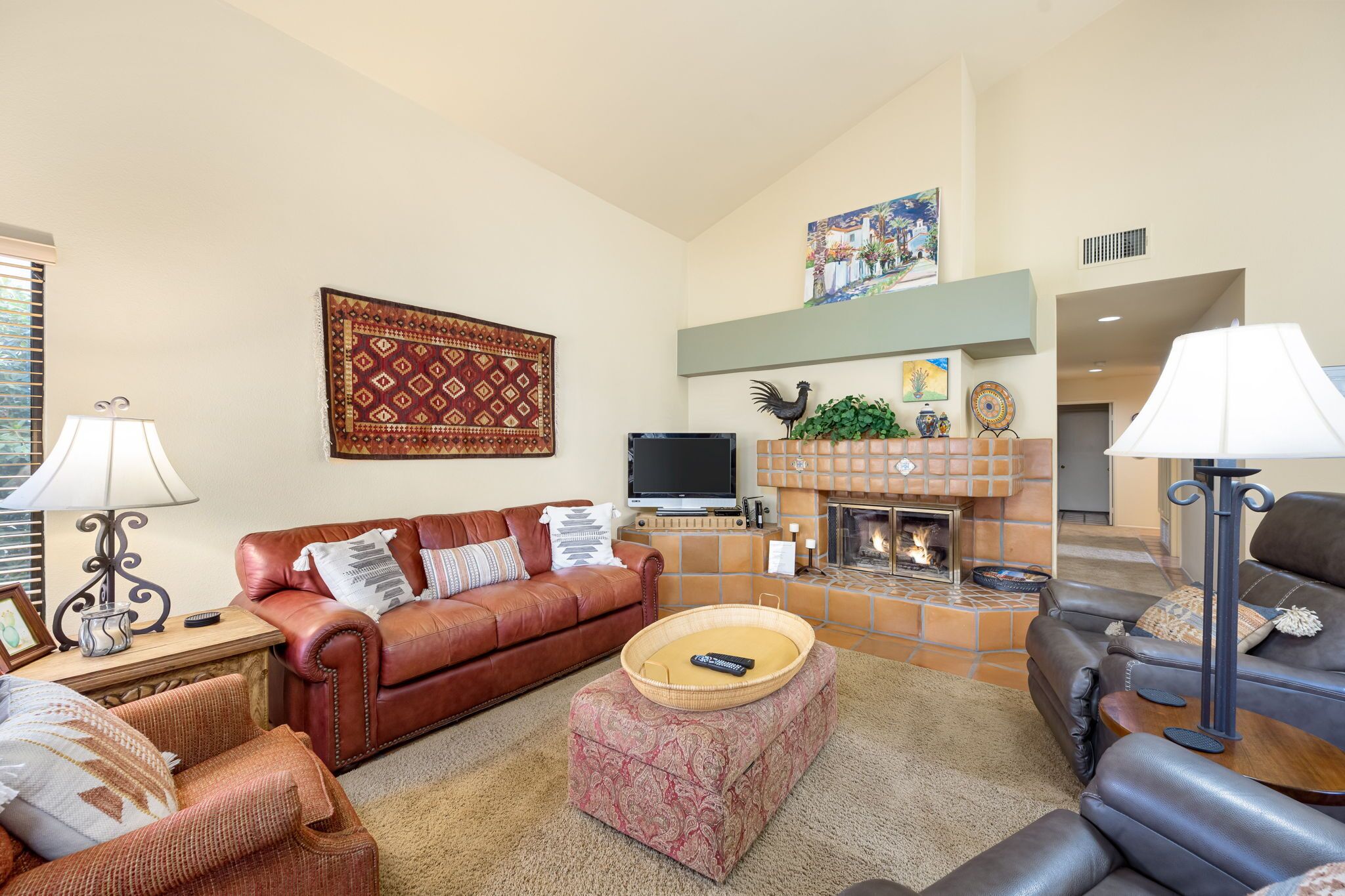 Ein Wohnzimmer mit Kamin, Ledersofas, einem Fernseher und einem gemusterten Teppich.
