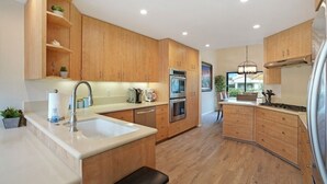 Una cocina moderna con armarios de madera, electrodomésticos de acero inoxidable y una isla central.