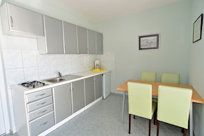 Compact kitchen with gas stove, sink, and coffee maker, adjacent to a dining area with a table and chairs.