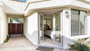 A house with a patio, a sliding glass door leading to a bedroom, and a small outdoor area with a garden. - Santa Rosa Cove #42, 3 BD /3.5 BA, Pet Friendly Home, Permit 063486 (La Quinta)