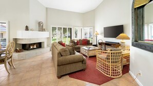 A living room with a fireplace, sofas, a TV, and a large window. - Santa Rosa Cove #42, 3 BD /3.5 BA, Pet Friendly Home, Permit 063486 (La Quinta)
