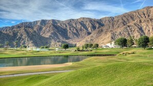 A golf course with a pond, mountains in the background, and a clubhouse. - Santa Rosa Cove #50, 3 Bedrooms   3.5 Baths  La Quinta City Permit 063498 (La Quinta)