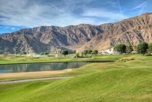 A golf course with a pond, mountains in the background, and a clubhouse. - Santa Rosa Cove #50, 3 Bedrooms 3.5 Baths La Quinta City Permit 063498 (La Quinta)