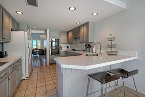 A modern kitchen with a large island, white cabinetry, and a view into the dining area. - Santa Rosa Cove #50, 3 Bedrooms 3.5 Baths La Quinta City Permit 063498 (La Quinta)