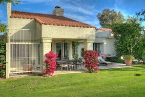 A house with a patio, outdoor furniture, and a fenced area with flowering plants. - Santa Rosa Cove #50, 3 Bedrooms   3.5 Baths  La Quinta City Permit 063498 (La Quinta)
