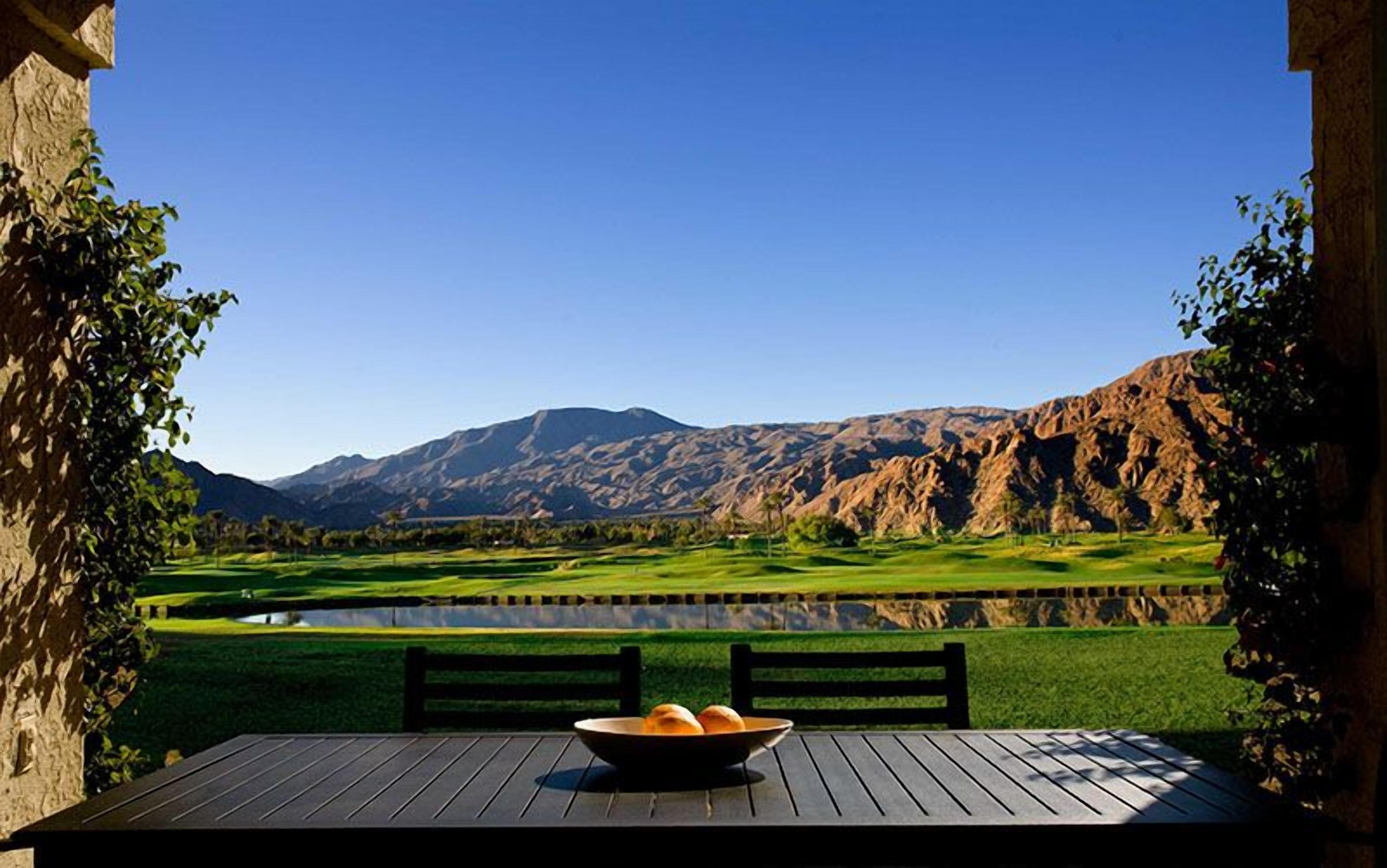 Une table avec un panier de pain et une vue sur un terrain de golf et des montagnes.