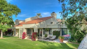 A two-story house with a tiled roof, a covered patio with outdoor furniture, and a well-maintained lawn. - Santa Rosa Cove #50, 3 Bedrooms   3.5 Baths  La Quinta City Permit 063498 (La Quinta)