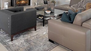 Ein modernes Wohnzimmer mit Kamin, einem wandmontierten Flachbildfernseher und einer gemütlichen Sitzecke mit Sofa und Sesseln.