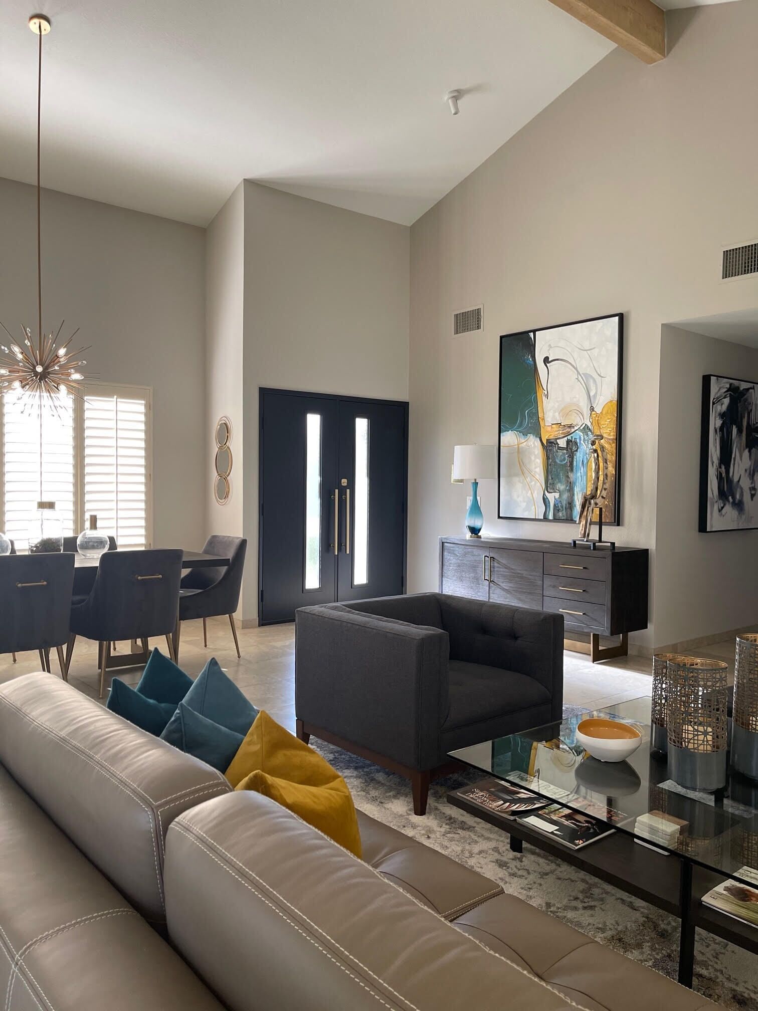 Un salon moderne avec un canapé en cuir, une table basse en verre et un coin repas doté d’un ensemble de salle à manger aux couleurs sombres.