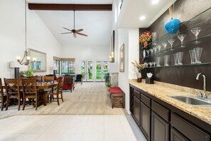 A modern kitchen with granite countertops, a built-in sink, and a glass display shelf. - Beautiful Home on Golf Course with Amazing Mtn Views! Permit 063495 (La Quinta)