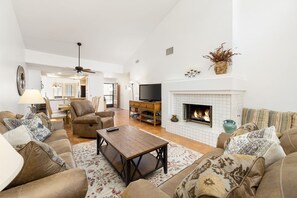 A spacious living room with a fireplace, leather sofas, a wooden coffee table, and a television.