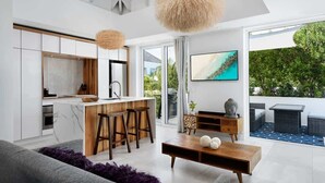 A modern kitchen with a central island, bar stools, and a dining area with a coffee table. - Studio w/ Private Plunge Pool (Long Bay Hills)
