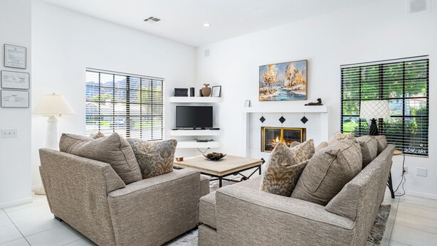 A modern living room with a fireplace, two sofas, a TV, and a painting. - Tennis Villa #10, Close to Festivals!   Pet Friendly Home.  Permit 063443 (La Quinta)