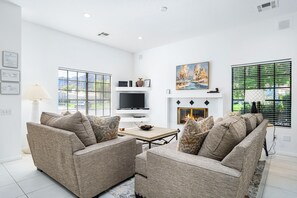A modern living room with a fireplace, two sofas, a TV, and a painting.