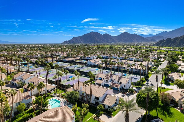 A resort with multiple villas, a central pool, and a mountainous backdrop.