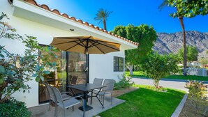 A patio with a table and chairs, a large umbrella, and a view of a mountain. - Tennis Villa #10, Close to Festivals!   Pet Friendly Home.  Permit 063443 (La Quinta)