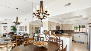 Una cocina amplia con electrodomésticos modernos, un comedor con mobiliario de madera y una lámpara de araña.